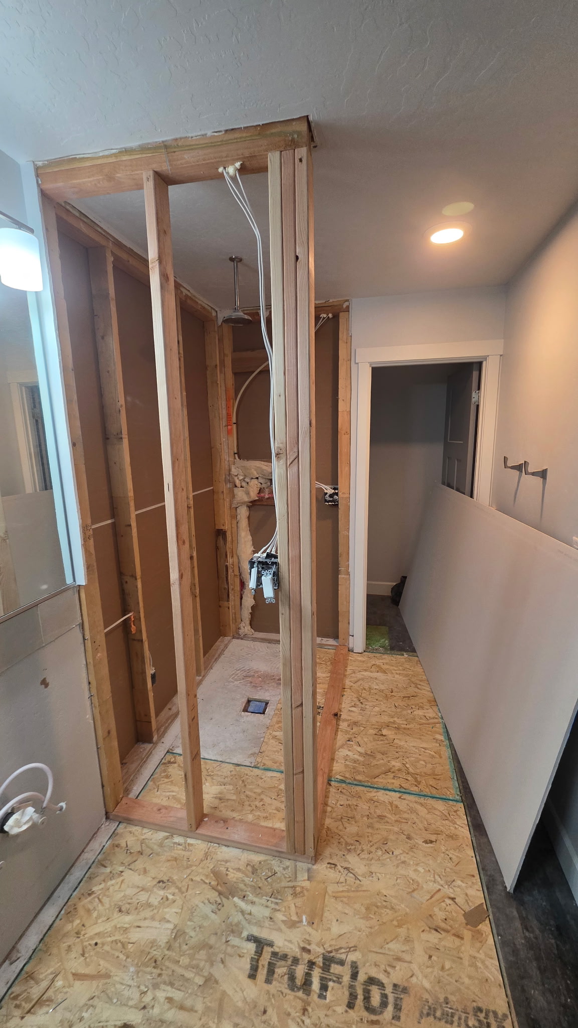 Bathroom renovation rough-in stage with shower framing and plumbing