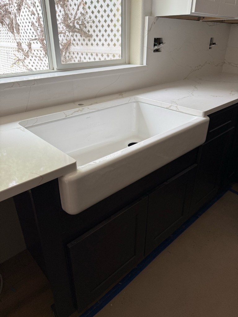Kitchen farmhouse sink with marble countertop and backsplash, dark shaker cabinets
