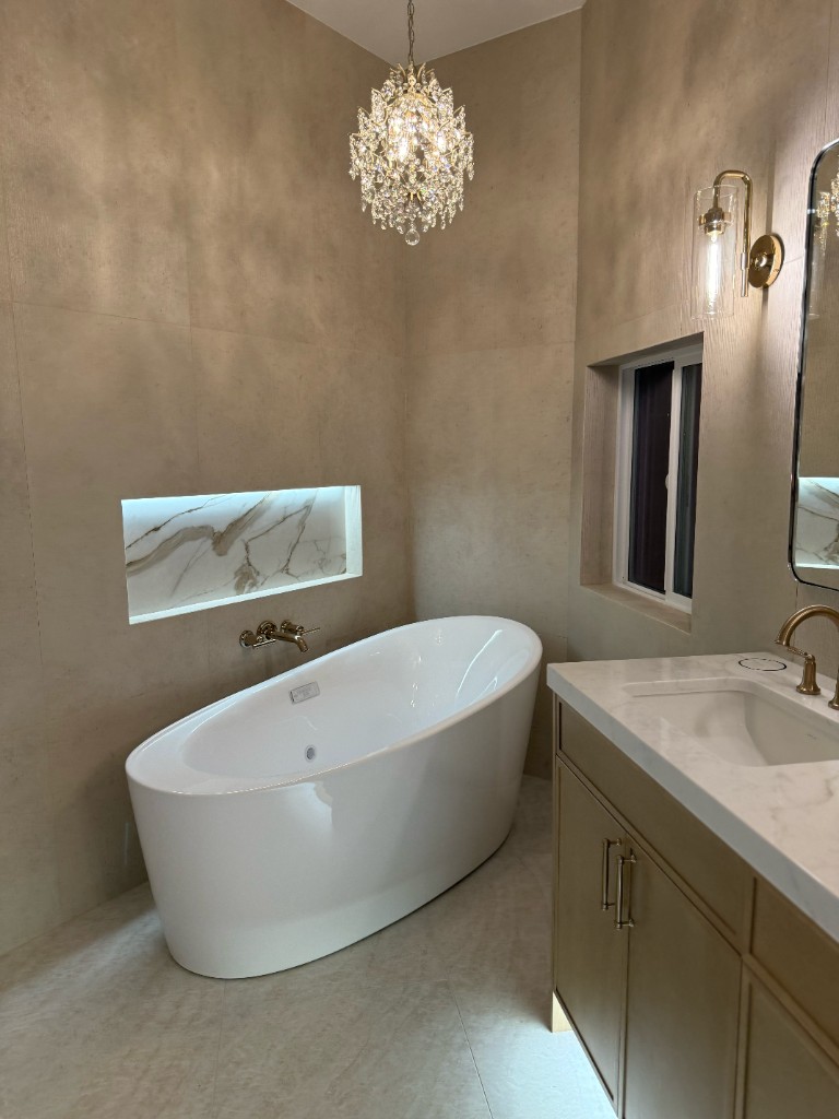 Luxury bathroom with freestanding tub, marble niche, and warm neutral tile
