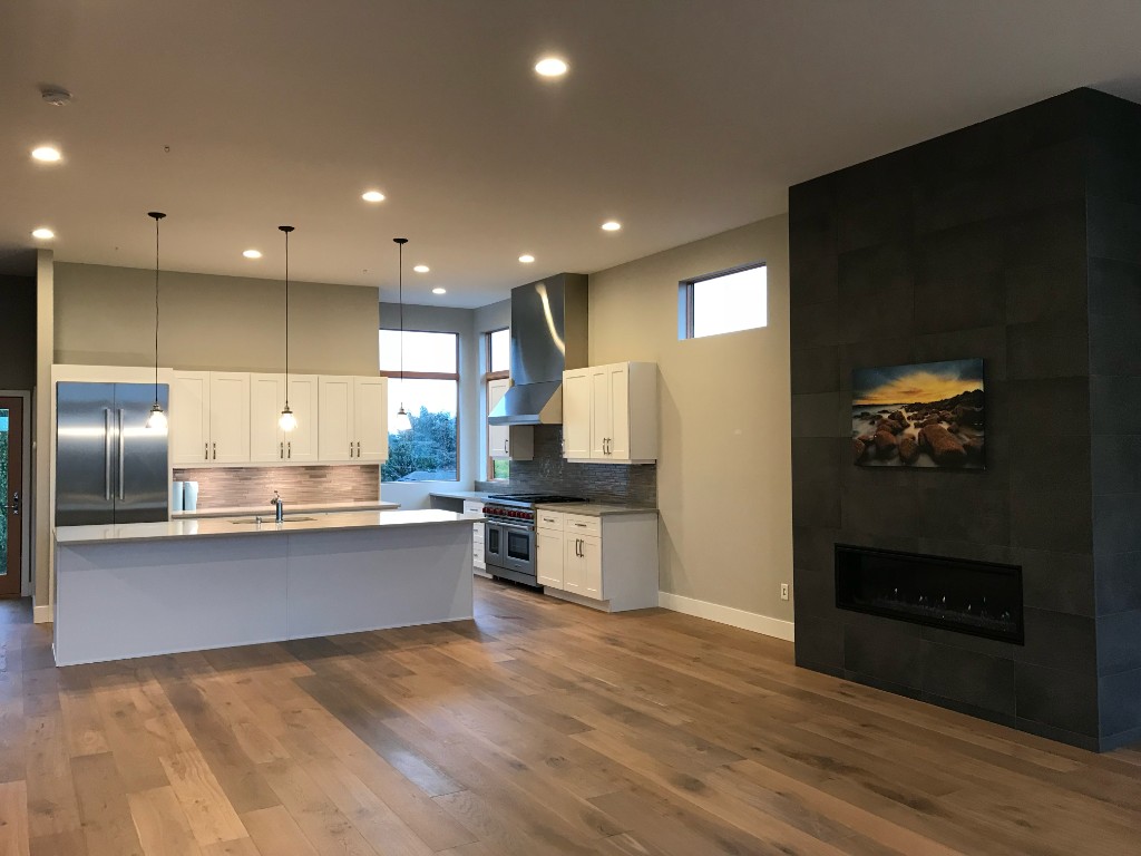 Open-concept kitchen and living area with custom tile fireplace wall