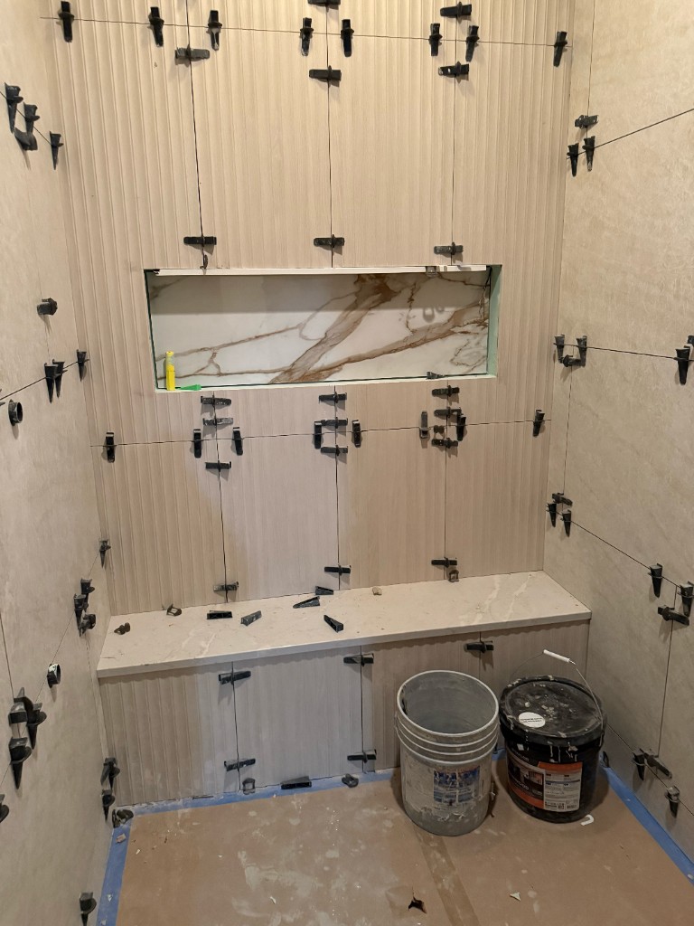 Custom shower tiling with fluted walls, marble niche, and built-in bench