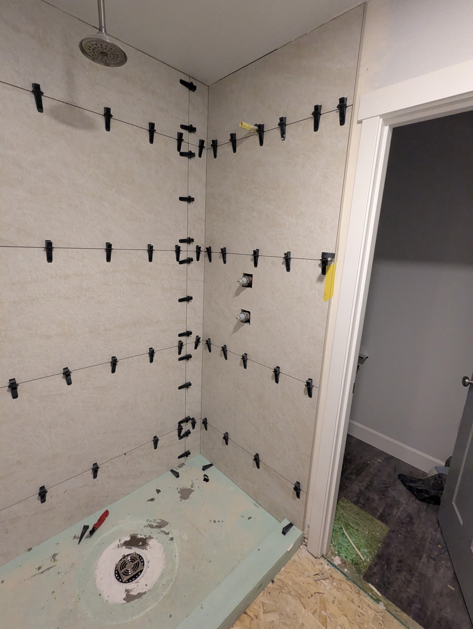 Custom shower tile installation in progress with large-format tiles and professional leveling spacers