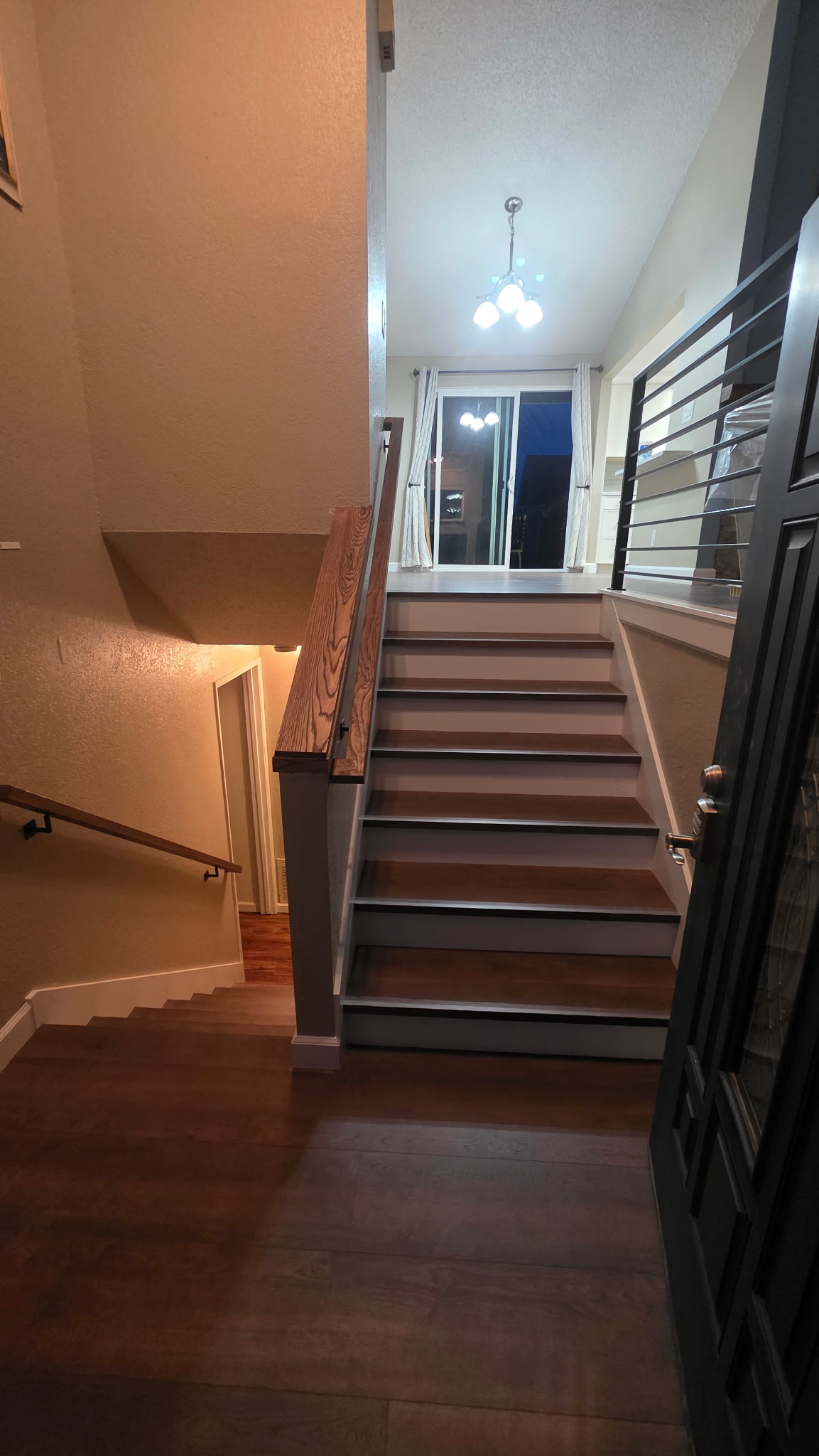 Split-level entryway with wood stairs and modern black metal railing