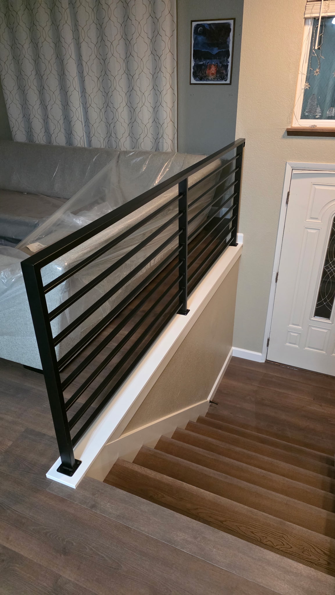 Modern staircase with black metal horizontal bar railing and wood treads