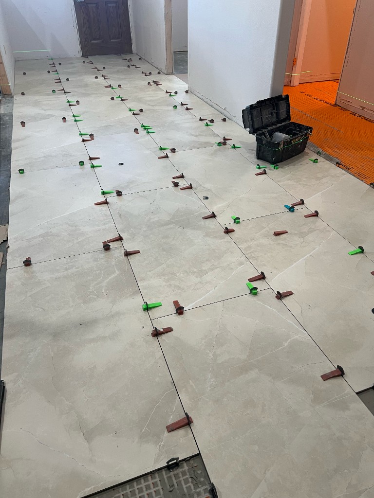 Large-format tile floor installation in progress with professional leveling system