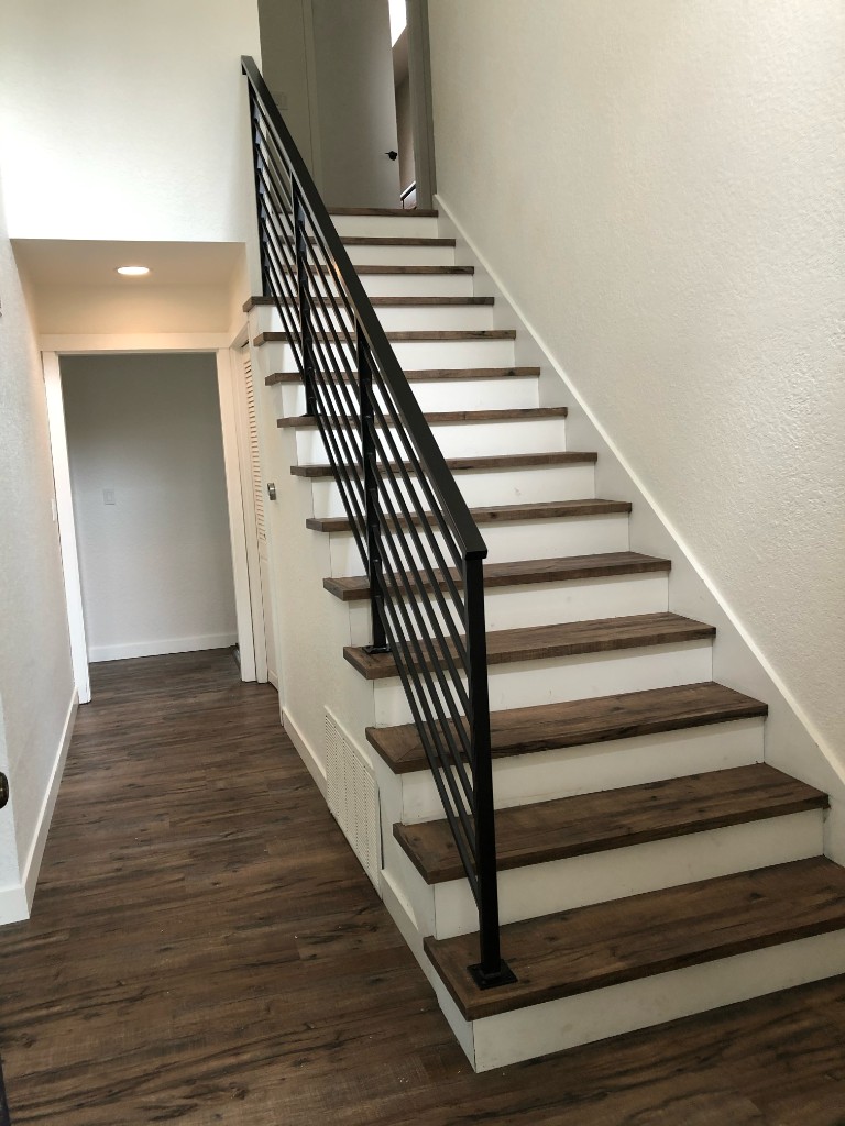 Modern staircase with dark wood-look treads, white risers, and black metal railing